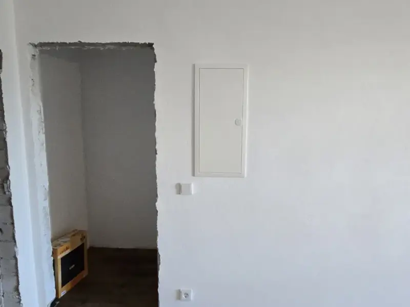 Heller, renovierter Raum mit Steckdosen und eingebauter Verteilertür in der Wand