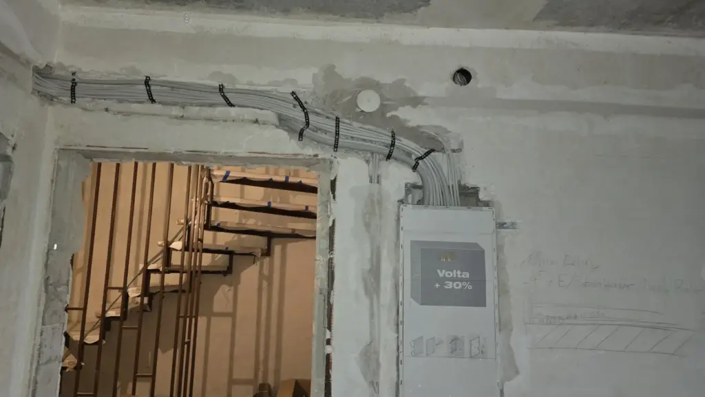 Gebündelte Leitungen an der Decke, die zu einer Unterputz-Verteilung in der Wand führen