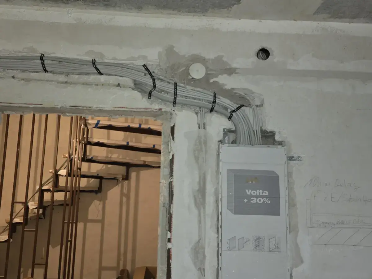 Gebündelte Leitungen an der Decke, die zu einer Unterputz-Verteilung in der Wand führen