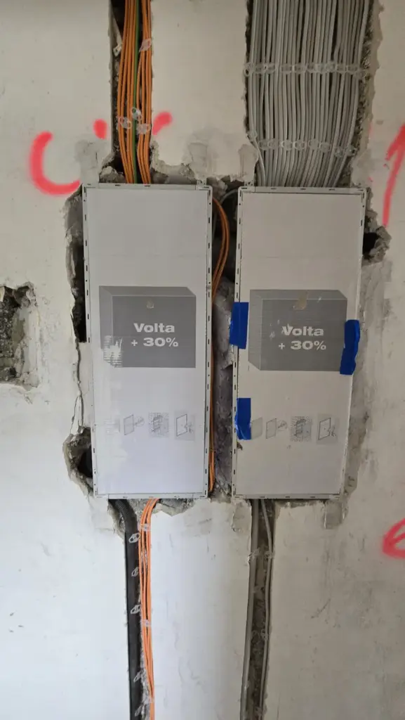 Zwei eingebaute Unterverteilungen in einer Wand mit zahlreichen zugeführten Leitungen