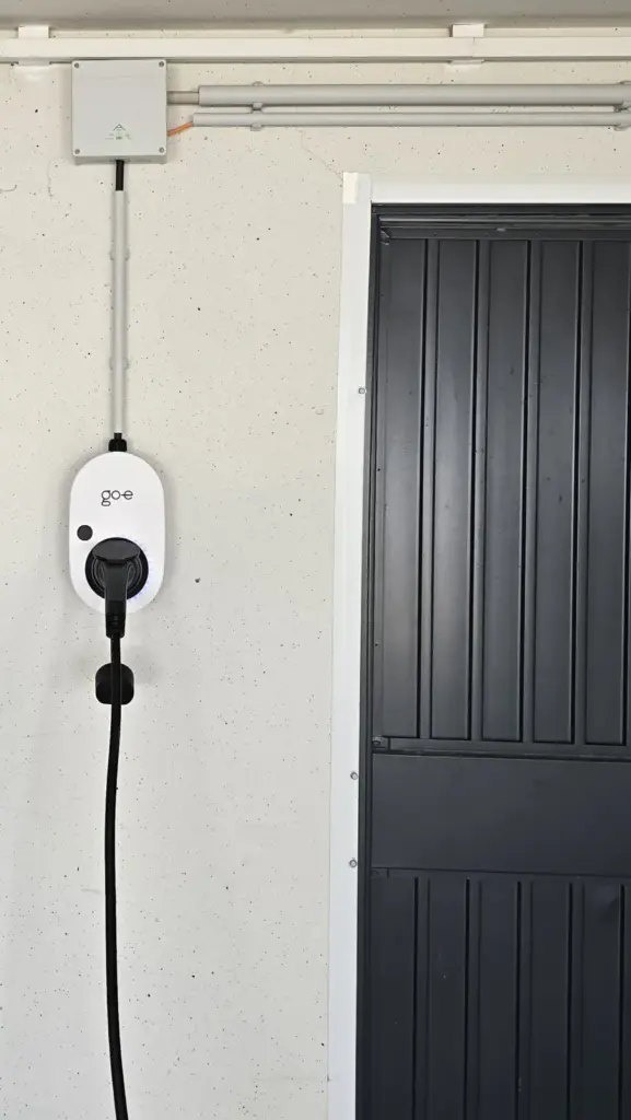 Weiße Wallbox mit Ladekabel an einer hellen Garagenwand