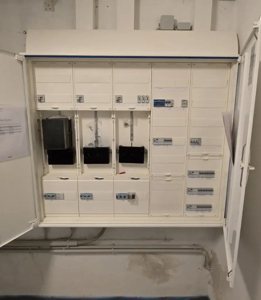 Geöffneter Zählerschrank mit mehreren Zählerplätzen und Sicherungsautomaten